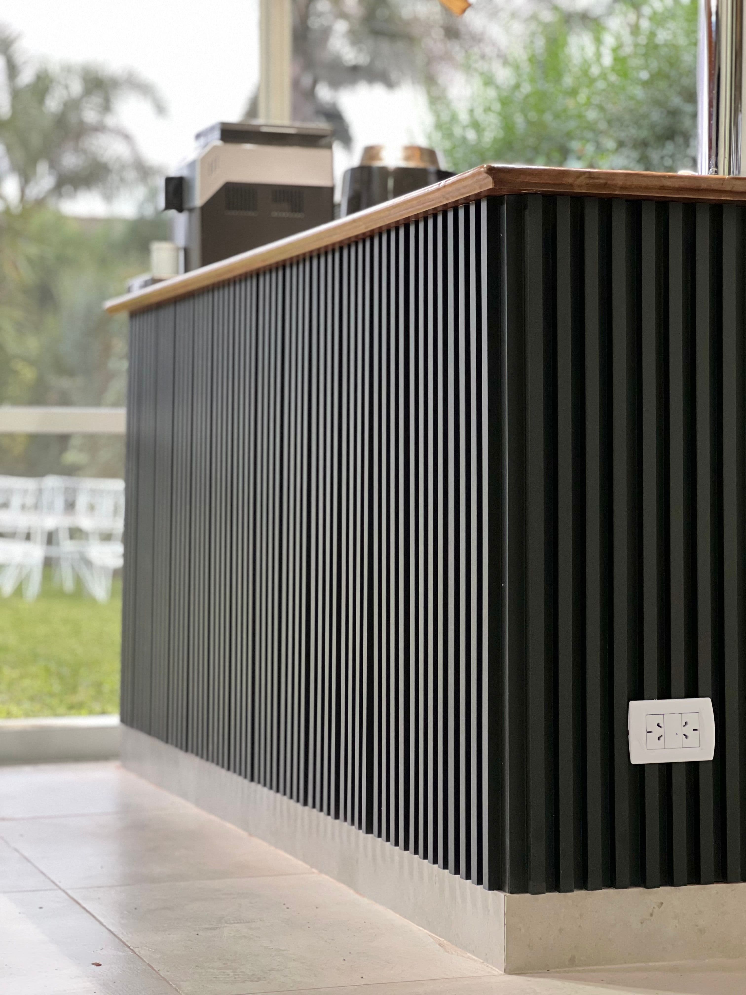barra con wall panels negros de wpc con un enchufe